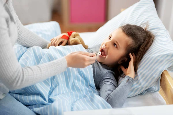 Mother giving cough syrup to sick daughter — Stock Photo, Image