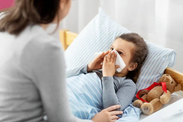 Matka z chorą córeczką dmuchanie nosa w łóżku — Zdjęcie stockowe