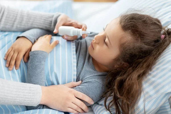 Mother with nasal spray treats sick daughter — Stock Photo, Image