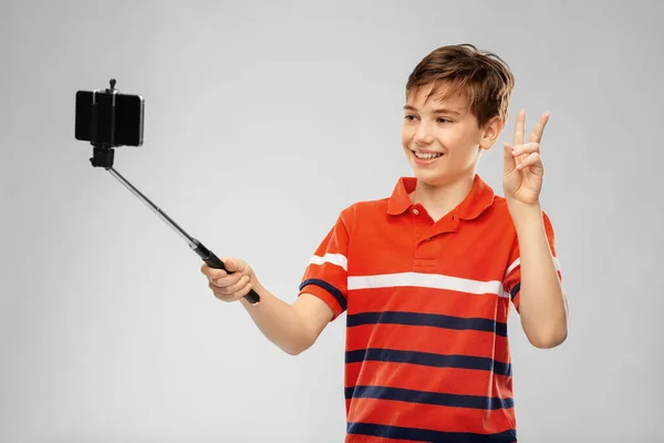 Chłopiec robi zdjęcia ze smartfonem na selfie stick — Zdjęcie stockowe