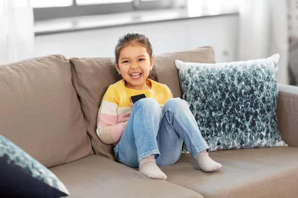 Heureuse petite fille souriante avec smartphone à la maison — Photo