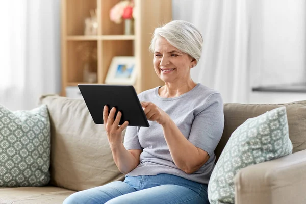 Glückliche Seniorin mit Tablet-PC zu Hause — Stockfoto