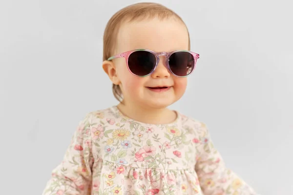 Happy little baby girl in sunglasses over grey — Stock Photo, Image