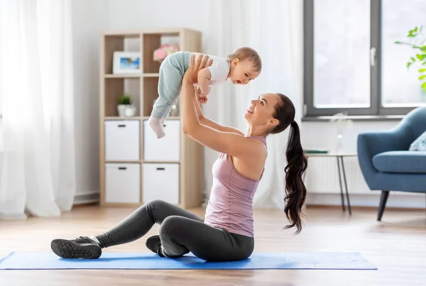 Glückliche Mutter mit kleinem Baby, das zu Hause Sport treibt — Stockfoto