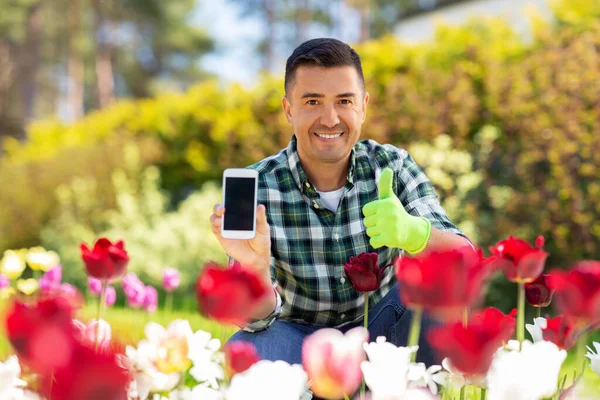 Mann mit Handy zeigt Daumen nach oben im Blumengarten — Stockfoto