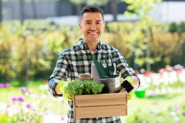 Hombre feliz con herramientas en caja en el jardín de verano — Foto de Stock