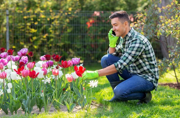 Man met bloemen roepen op smartphone in de tuin — Stockfoto