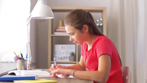 Student dziewczyna z książki pisania do notebooka w domu — Wideo stockowe