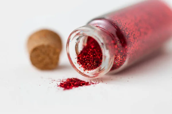 Red glitters poured from small glass bottle — Stock Photo, Image