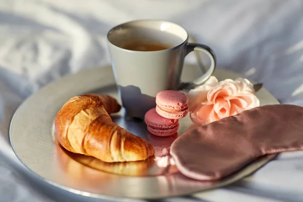 Croissant, maschera per dormire occhi e caffè a letto — Foto Stock