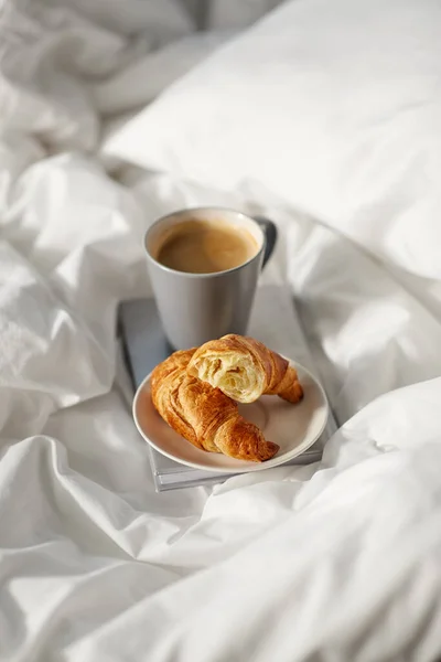 Cornetti, tazza di caffè e prenotare a letto a casa — Foto Stock