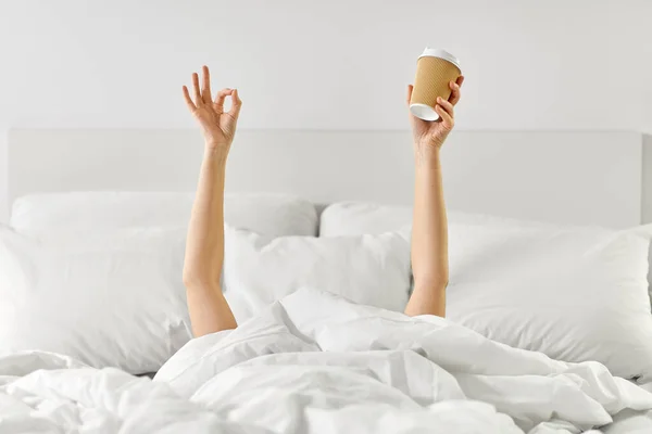 Nő csésze kávé fekszik az ágyban mutatja rendben — Stock Fotó
