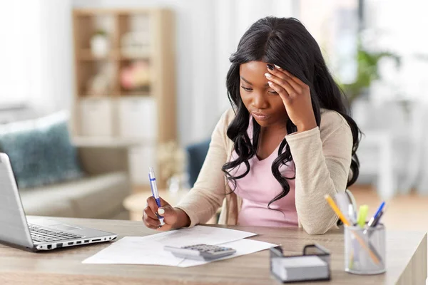 Mujer con calculadora y papeles trabajando en casa — Foto de Stock