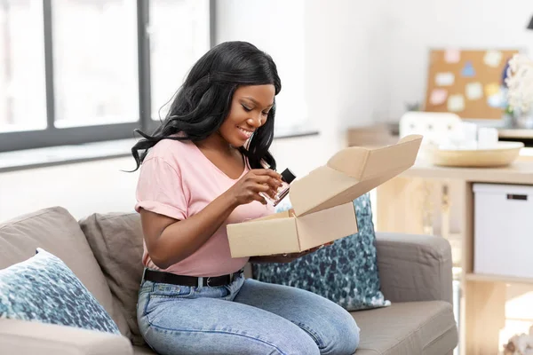Африканская американка открывает коробку с посылками дома — стоковое фото