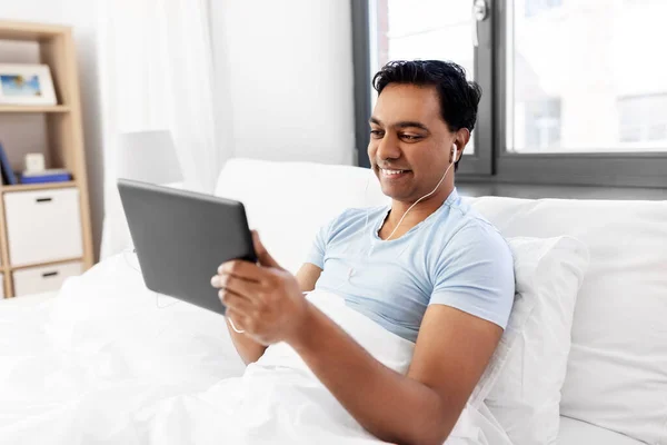 Hombre indio feliz con la tableta PC en la cama en casa — Foto de Stock