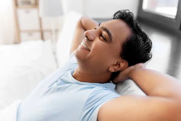 Šťastný usmívající se indián muž protahování v posteli doma — Stock fotografie
