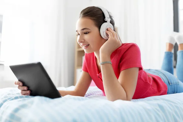戴耳机在平板电脑上听音乐的女孩 — 图库照片