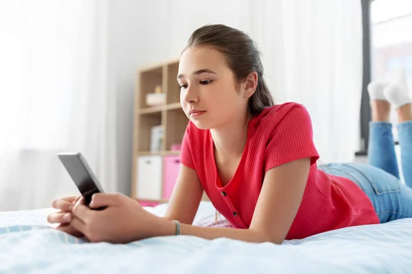 Smutna nastolatka smsy na smartfonie w domu — Zdjęcie stockowe