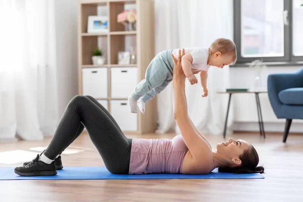 Glückliche Mutter mit kleinem Baby, das zu Hause Sport treibt — Stockfoto