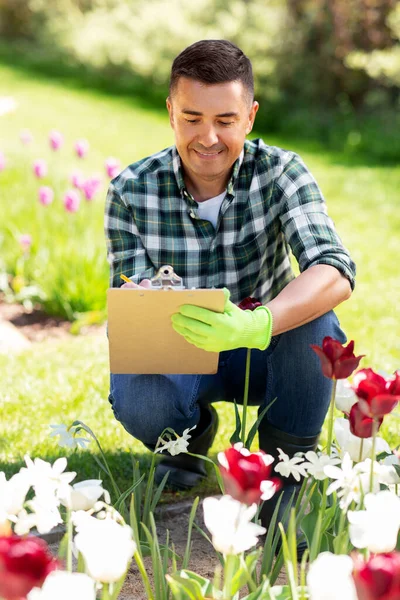 带着剪贴板和鲜花的男人在夏日花园 — 图库照片