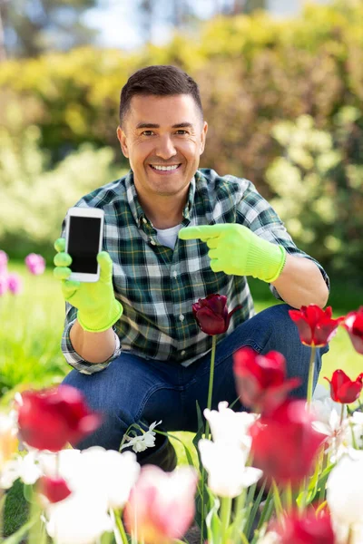 Mężczyzna w średnim wieku ze smartfonem w ogrodzie kwiatowym — Zdjęcie stockowe