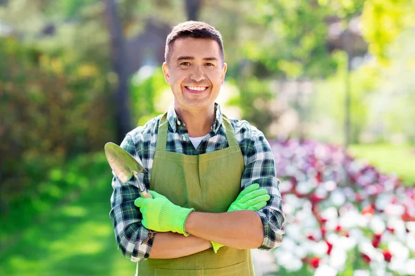 Glücklicher Mann in Schürze mit Schaufel im Sommergarten — Stockfoto