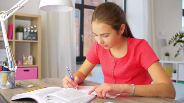 Student girl with book writing to notebook at home — Stock Video