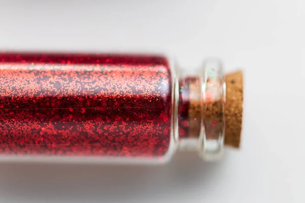 Rött glitter i flaska över vit bakgrund — Stockfoto