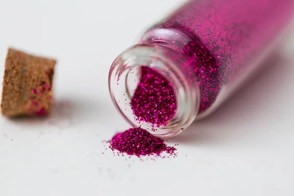 Purpurina rosa vertida de una pequeña botella de vidrio —  Fotos de Stock
