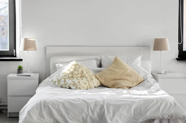 Acogedor dormitorio con cojines y ropa de cama en casa — Foto de Stock
