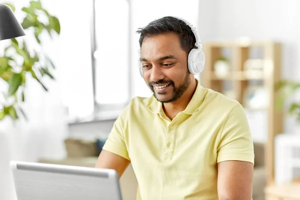 Mężczyzna w słuchawkach z laptopem pracujący w domu — Zdjęcie stockowe
