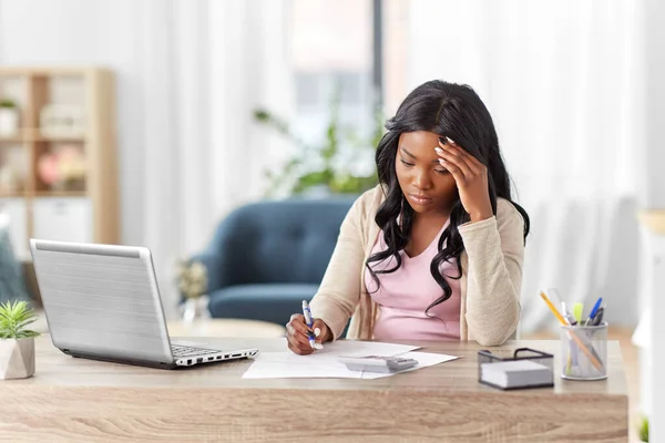 Femme avec calculatrice et papiers travaillant à la maison — Photo