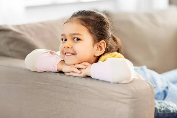 Glad leende liten flicka ligger på soffan hemma — Stockfoto