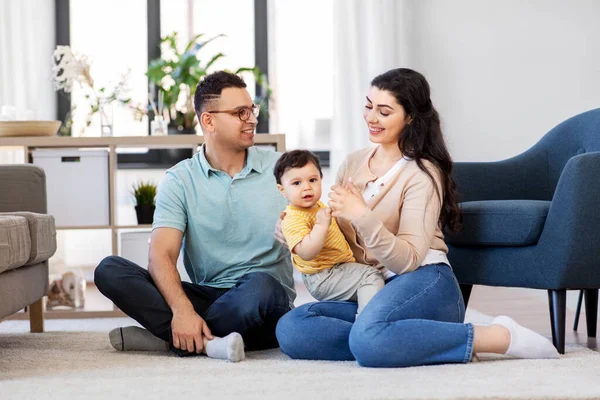 Счастливая семья с ребенком, сидящим на полу дома — стоковое фото