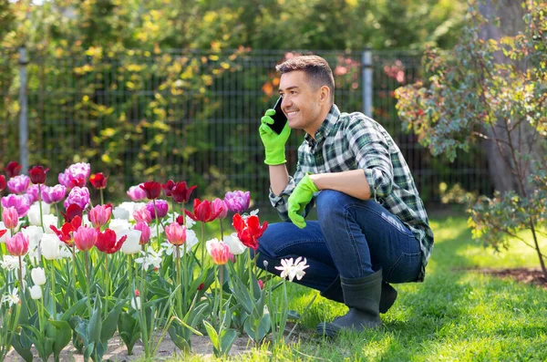 Homme avec des fleurs appelant sur smartphone au jardin — Photo