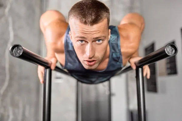 Man doing push-ups on parallel bars in gym — Stock Photo, Image