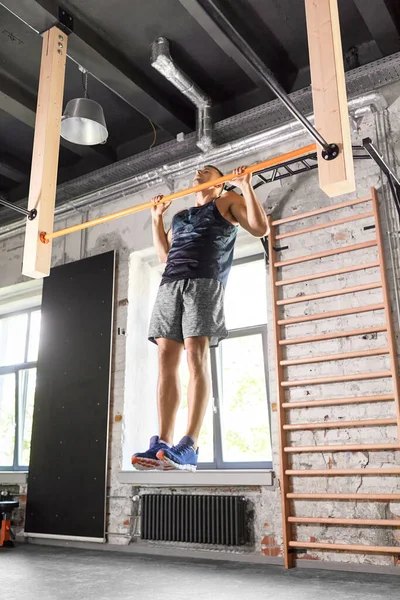 Hombre haciendo ejercicio en la barra y haciendo pull-ups en el gimnasio — Foto de Stock