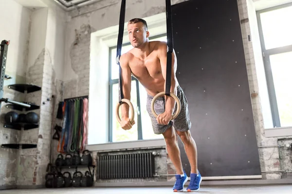 Muž dělá kliky na gymnastické kroužky v tělocvičně — Stock fotografie