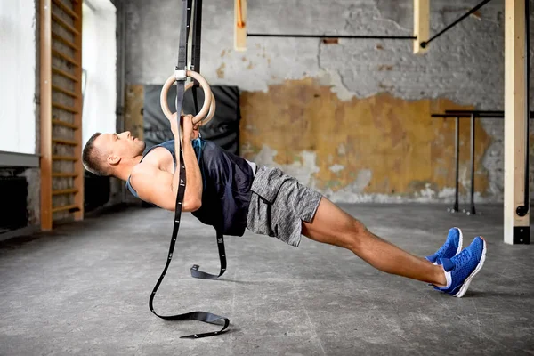 Homme faisant de l'exercice sur les anneaux de gymnastique dans la salle de gym — Photo