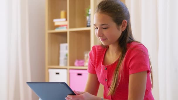 집 침대에 앉아 있는 태블릿 PC 를 들고 웃는 소녀 — 비디오