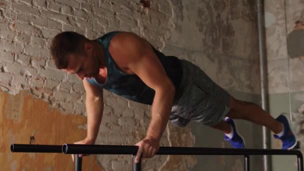 Hombre haciendo flexiones en barras paralelas en el gimnasio — Vídeo de stock