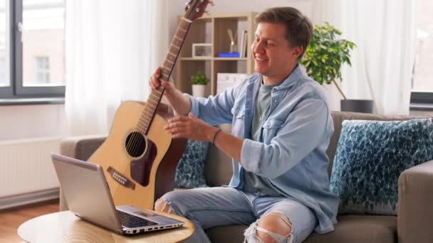 Anak muda dengan laptop bermain gitar di rumah — Stok Video