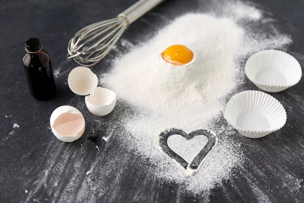 Flour, egg, whisk and paper baking molds on table — Stock Photo, Image