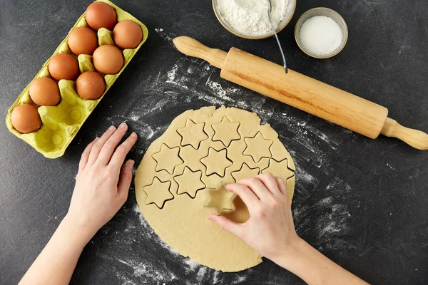 Mains de coupe de pâte avec moule étoile sur la table — Photo