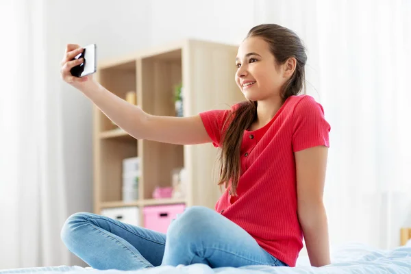 Glad flicka med smartphone tar selfie hemma — Stockfoto