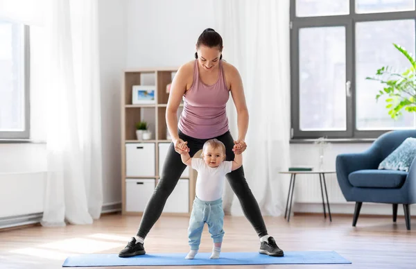 Glückliche Mutter mit kleinem Baby, das zu Hause Sport treibt — Stockfoto