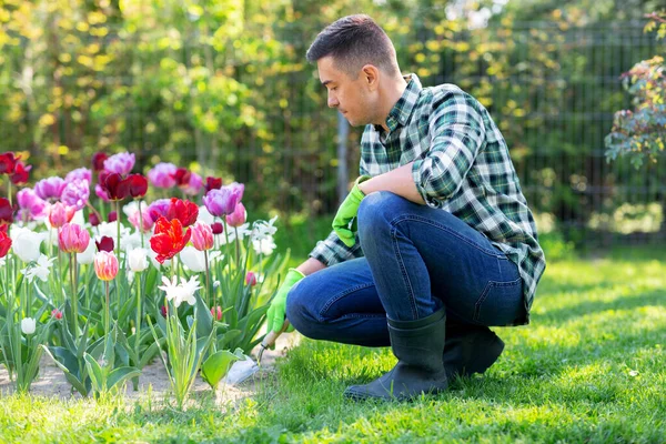 Άνθρωπος με σέσουλα φροντίδα των λουλουδιών στον κήπο — Φωτογραφία Αρχείου