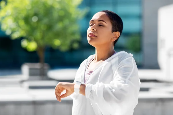 Jeune femme avec montre intelligente respirant à l'extérieur — Photo