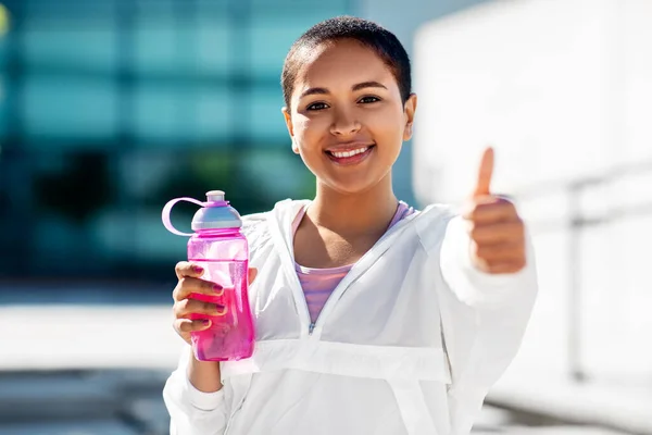 Mujer feliz con botella de agua mostrando los pulgares hacia arriba — Foto de Stock