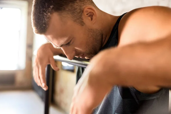 Close up of tired man at parallel bars in gym — Stock Photo, Image